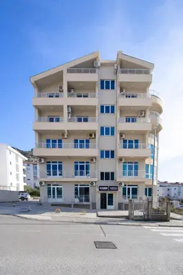 a tall apartment building in a parking lot at Apartment Sofija in Budva
