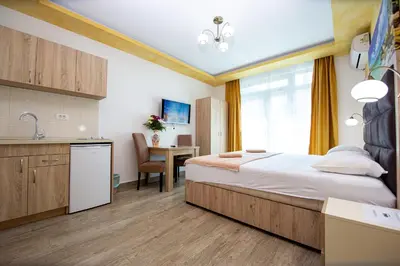 a bedroom with a bed and a kitchen and a table at Apartment Sofija in Budva