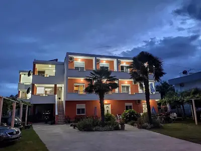 a building with two palm trees in front of it at Casa ROBI - Apartments in Ulcinj