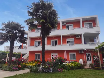 a building with palm trees and flowers in front of it at Casa ROBI - Apartments in Ulcinj