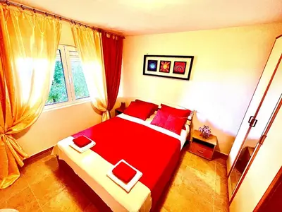 a bedroom with a red bed and a window at Holiday Home Viko in Sutomore