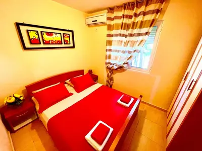 a bedroom with a red bed and a window at Holiday Home Viko in Sutomore