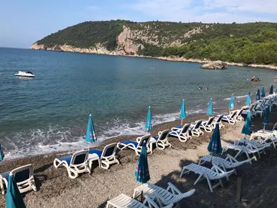 a row of chairs and umbrellas on a beach at Holiday Home Viko in Sutomore