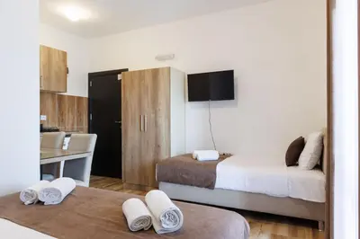 a room with two beds and a desk with a tv at Apartments Donna in Bar
