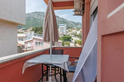 a table with an umbrella on a balcony with a view at Apartments Donna in Bar