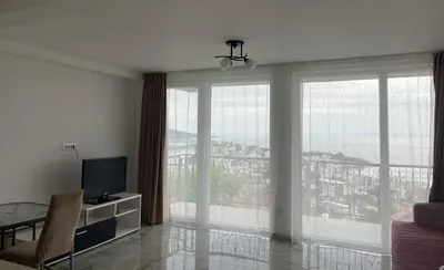 a living room with a television and large windows at Apartment Light House in Dobra Voda