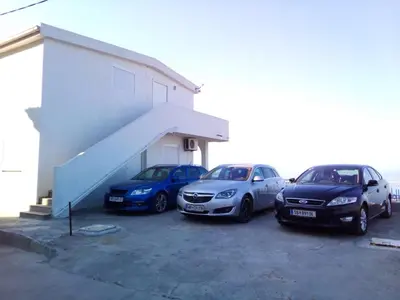 three cars parked in a parking lot next to a building at Apartment Light House in Dobra Voda