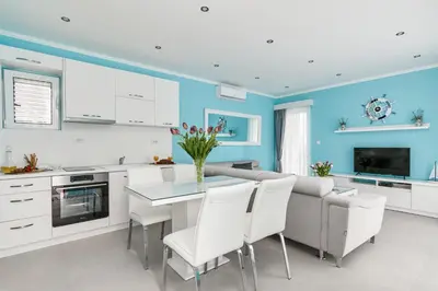 a kitchen with blue walls and a table with white chairs at Apartment Kascelan in Kotor