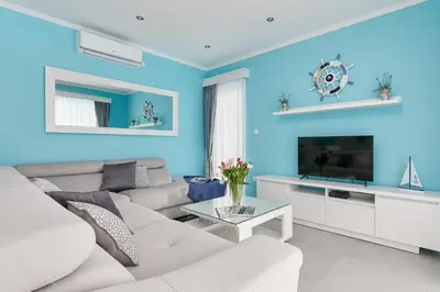 a blue living room with a white couch and a tv at Apartment Kascelan in Kotor