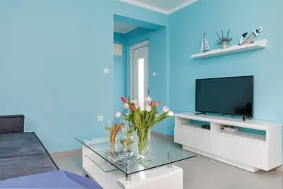 a living room with a tv and a blue wall at Apartment Kascelan in Kotor