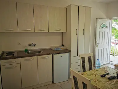a kitchen with wooden cabinets and a table with a tableablish at Guest House Levant in Čanj
