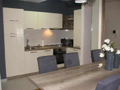 a kitchen with white cabinets and a wooden table at Apartments B&S Lux in Budva