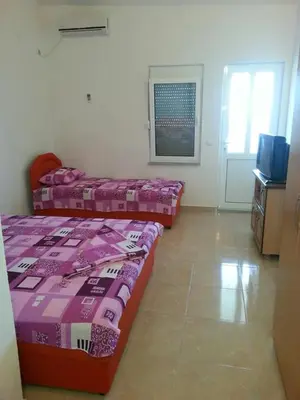 a room with two beds and a television in it at Apartments Dukat in Ulcinj