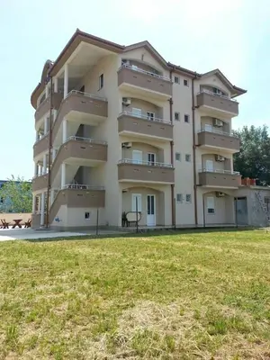a large building with a grass field in front of it at Apartments Dukat in Ulcinj
