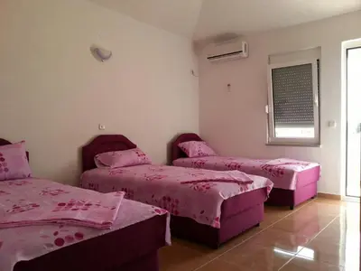 a room with three beds with pink sheets and a window at Apartments Dukat in Ulcinj