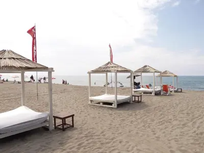 a group of beds on a beach with the ocean at Apartments Dukat in Ulcinj