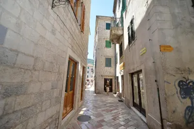 an alley with buildings and a person walking down the street at Apartmani Art Karampana in Kotor