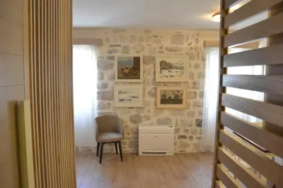 a room with a chair and a wall with pictures at Apartmani Art Karampana in Kotor