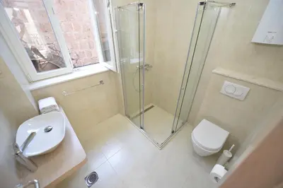 a bathroom with a shower and a toilet and a sink at Apartmani Art Karampana in Kotor