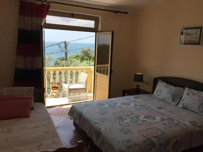 a bedroom with a bed and a balcony with a chair at Apartment Spuza in Ulcinj