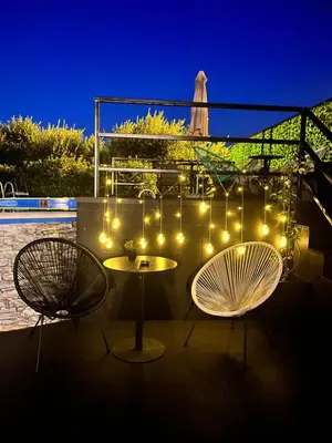 a patio with two chairs and a table and lights at Q PODGORICA Beds,Rooms and more in Podgorica