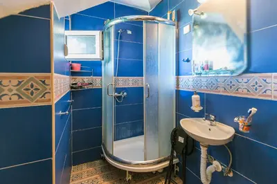 a blue bathroom with a shower and a sink at Q PODGORICA Beds,Rooms and more in Podgorica