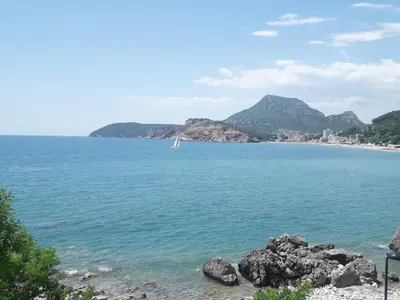 a view of a beach with a sail boat in the water at Two Palms Apartment in Sutomore