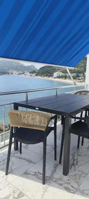 a table and a bench on a balcony with the ocean at Two Palms Apartment in Sutomore