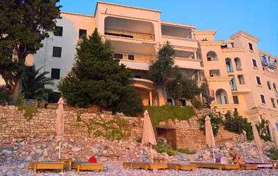 a building with umbrellas and benches in front of it at Apartments Zezelj in Sveti Stefan