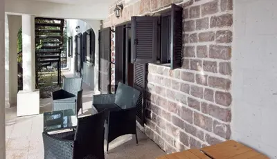 a patio with black chairs and a brick wall at Apartments Zezelj in Sveti Stefan