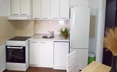 a white kitchen with a sink and a refrigerator at Apartments Zezelj in Sveti Stefan