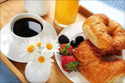 a plate with a croissant and a cup of coffee and strawberries at Kazablanka Rooms Aerodrom in Podgorica