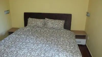 a bed with a gray comforter and a pillow at Kazablanka Rooms Aerodrom in Podgorica