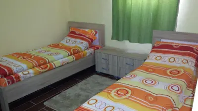 two beds in a room with green curtains at Kazablanka Rooms Aerodrom in Podgorica