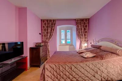 a bedroom with pink walls and a bed and a television at Kotor old town Palace Bucha in Kotor