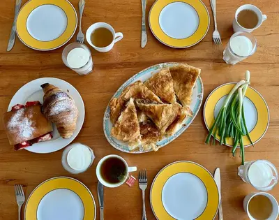a table with plates of food and cups of coffee at Apartmani Novkovic in Bar