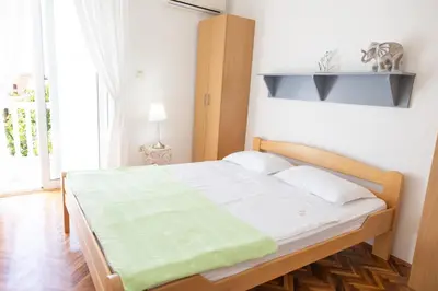 a bedroom with a bed with a green blanket on it at Apartmani Novkovic in Bar