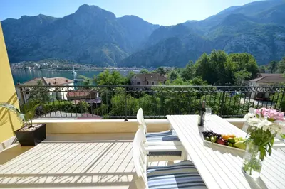 a balcony with a table and chairs and mountains at Posto Capitano C Group in Kotor