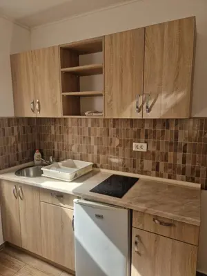 a kitchen with wooden cabinets and a sink at Apartmani Sijaric in Dobra Voda