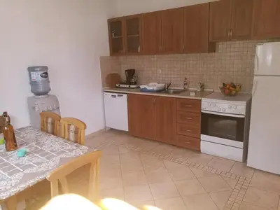 a kitchen with a table and a white refrigerator at Apartmani Sijaric in Dobra Voda