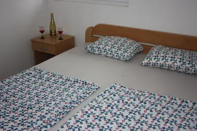 a bed with two pillows and two glasses of wine at Apartmani Sijaric in Dobra Voda