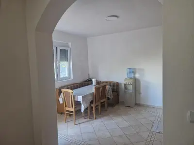a dining room with a table and chairs and a refrigerator at Apartmani Sijaric in Dobra Voda