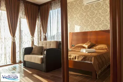 a bedroom with a bed and a couch next to a window at Hotel Velkom in Sutomore