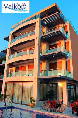 a building with a swimming pool in front of it at Hotel Velkom in Sutomore