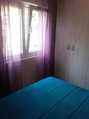 a bedroom with a blue bed with a window at Apartman Bećir in Budva
