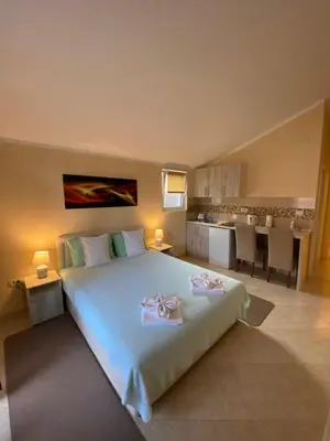 a bedroom with a large bed and a kitchen at Apartmani Raskovic in Budva