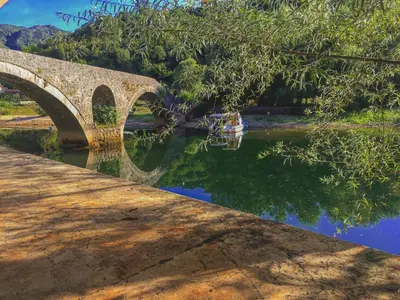a boat in the water under a bridge at Estate & Winery San Duyevo in Rijeka Crnojevića