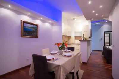 a dining room with a table and a kitchen at Apartment Mitrovic in Budva