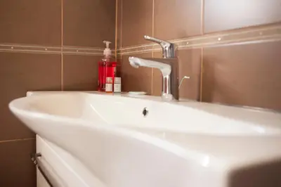 a bathroom sink with a red soap bottle on it at Apartment Mitrovic in Budva