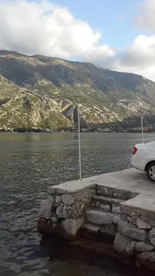 a white car parked next to a body of water at Apartment Radovic in Kotor